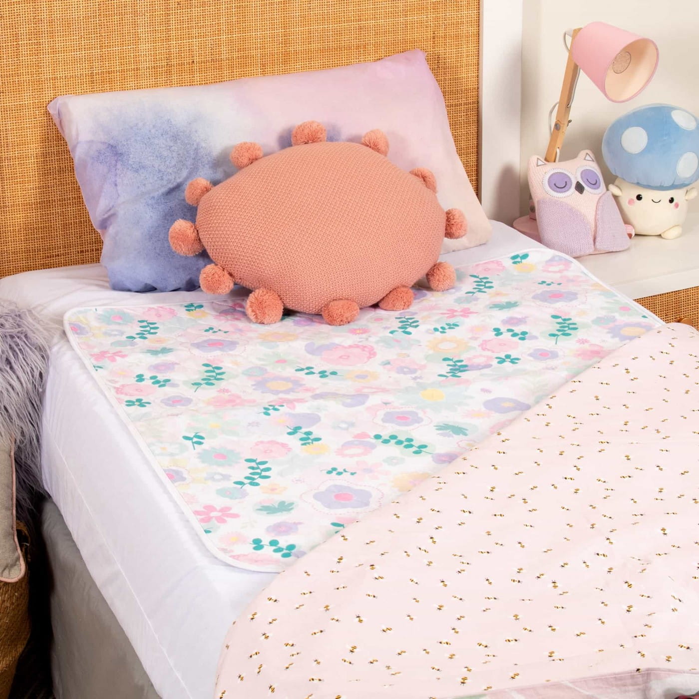 Flower Print Conni Kids bed pad on a child’s bed with colourful cushions
